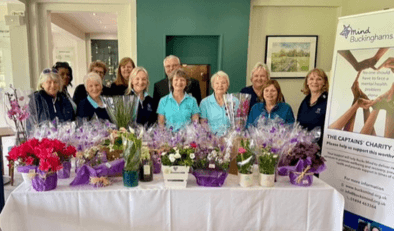 Members of golf club smiling with floral display