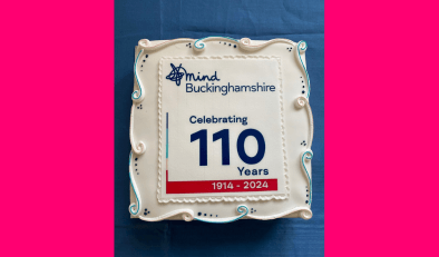 A large square cake with the Buckinghamshire Mind 110th anniversary logo on the top.