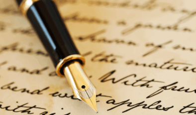 A fountain pen laid on top of paper with handwriting in ink.
