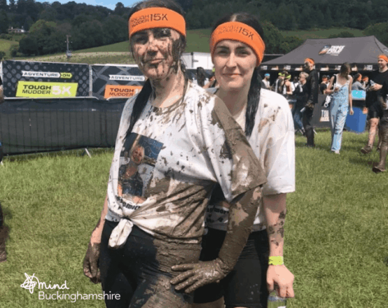 Two young people standing together and smiling after completing the Tough Mudder challenge.