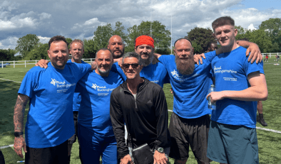 A group of men wearing Bucks Mind t-shirts with their arms around each other and smiling.